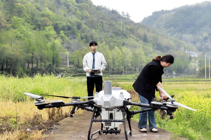 BeiDou w rolnictwie — dron na chińskim polu BeiDou w rolnictwie: pracownicy przygotowują drona do badań zasobów gruntów rolnych w Chinach