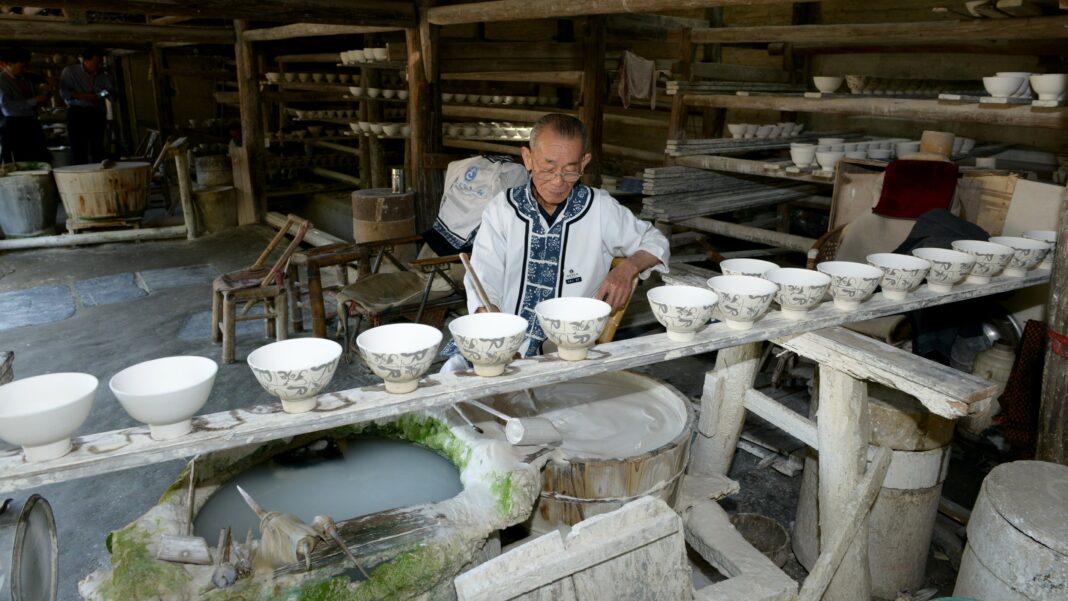 Jingdezhen – tradycyjna produkcja chińskiej porcelany Rzemieślnik zdobi porcelanowe czarki w tradycyjnym warsztacie w Jingdezhen