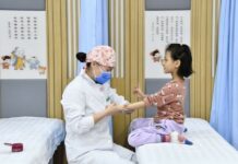 Tradycyjna medycyna chińska. Chiny stawiają na powiaty, badania i AI Lekarka tradycyjnej medycyny chińskiej wykonuje masaż dziecku w centrum zdrowia społeczności