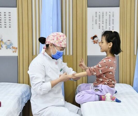 Tradycyjna medycyna chińska. Chiny stawiają na powiaty, badania i AI Lekarka tradycyjnej medycyny chińskiej wykonuje masaż dziecku w centrum zdrowia społeczności