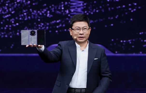 Richard Yu Chengdong trzyma rozłożony smartfon Huawei Mate XT 2 podczas prezentacji na scenie.