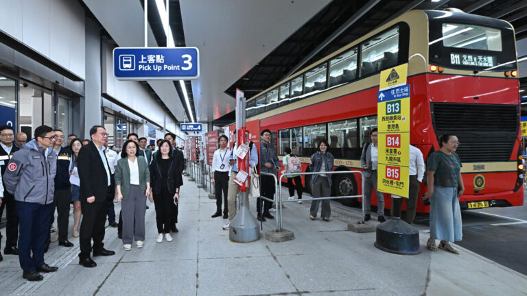 Piętrowy autobus przy przystankach nowego przejścia Huanggang oraz wizytujący je urzędnicy.
