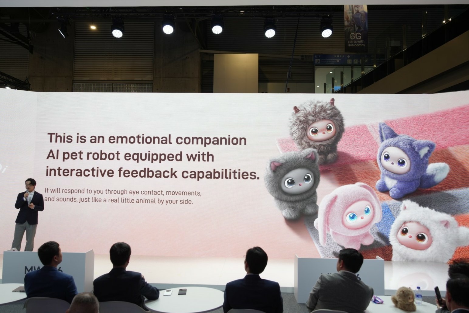 Konferencja nubii na MWC 2026, ekran pokazuje kolorowe roboty iMoochi, przed nim stoi prezenter i siedzą widzowie