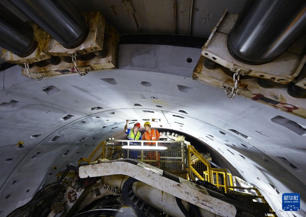 Dwaj pracownicy kontrolują konstrukcję wewnątrz maszyny drążącej tunel pod Zatoką Jiaozhou.