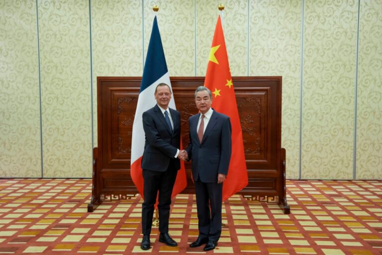 Wang Yi i Emmanuel Bonne podają sobie ręce na tle flag Chin i Francji podczas spotkania w Datong 10 października 2026 roku
